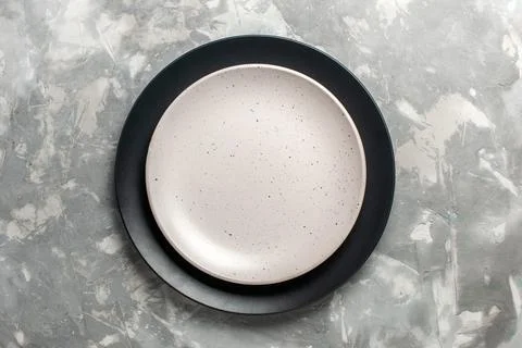 Top view round empty plate black colored with white plate on grey desk plat.. Stock Photos