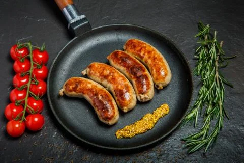 Top view round pan with four fried sausages and granular mustard 写真素材