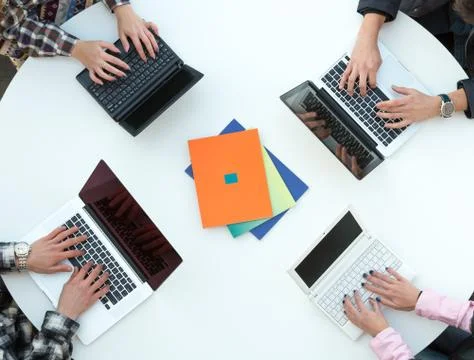 Top View of Rounded Desk with Four Laptops and People Hands Stock Photos