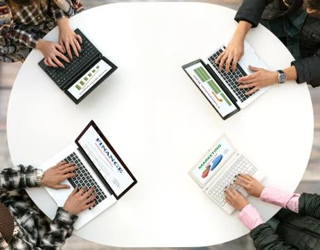 Top View of Rounded Desk with Four Laptops and People Hands Typing on Keyboard Foto stock