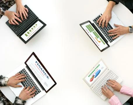 Top View of Rounded Desk with Four Laptops and People Hands Typing on Keyboard Stock Photos