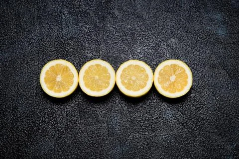 Top view of row of cut lemons on black background Stock Photos