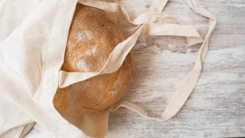 Top view on rustic bread into a natural linen bag on wood. Stock Photos