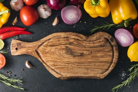 Top view of the rustic cutting board on the black kitchen table among fresh v Stock Photos