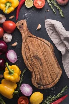 Top view of the rustic cutting board on the black kitchen table among fresh v Stock Photos