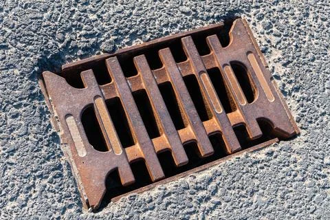 Top view of a rusty cast iron storm drain grate. Stock Photos