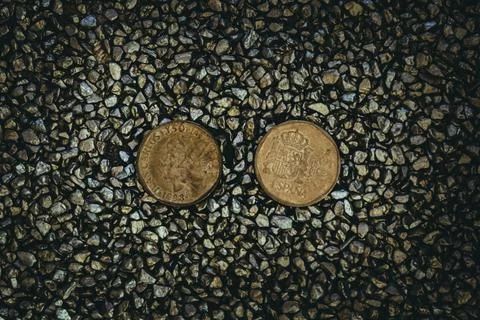 A top view of rusty old and worn out coins placed on the ground with tiny sto 库存照片