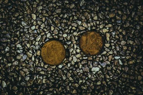 A top view of rusty old and worn out coins placed on the ground with tiny sto 库存照片
