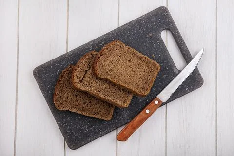 Top view of rye bread slices and knife on cutting board on wooden background Foto stock
