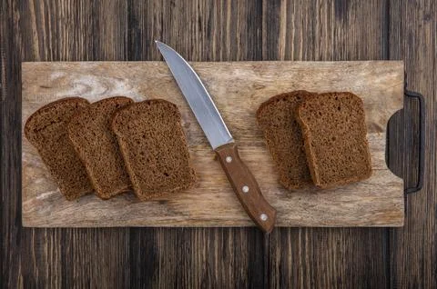 Top view of rye bread slices and knife on cutting board on wooden background Foto stock