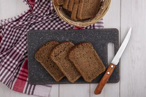 Top view of rye bread slices with knife on cutting board and in basket on p.. Foto stock