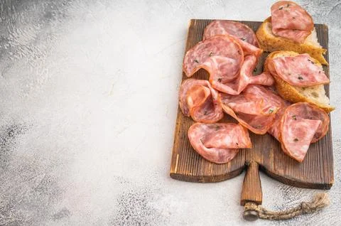 Top view salami  slices with bread on rustic wooden board with peppercorns .. Stock Photos