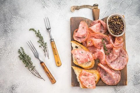 Top view salami  slices with bread on rustic wooden board with peppercorns .. Stock Photos