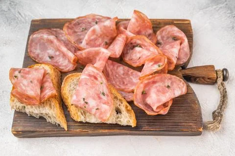 Top view salami  slices with bread on rustic wooden board with peppercorns .. Stock Photos