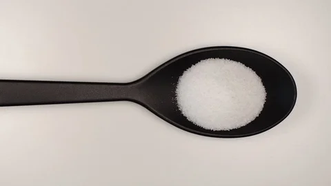 TOP VIEW: Salt fill a black plastic spoon on a table - Stop motion Stock Footage 124623070