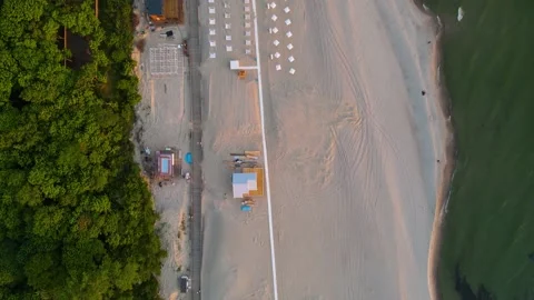 Top view of sandy beach on the sea coast with umbrellas and forest at sunset, Stock Footage 155809192