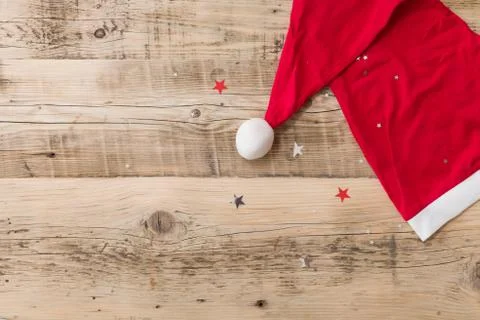 Top view on Santa's hat on retro wooden background with shiny stars. Stock Photos