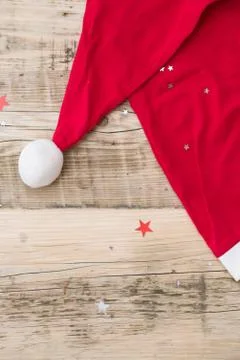 Top view on Santa's hat on retro wooden background with shiny stars. Christma Stock Photos