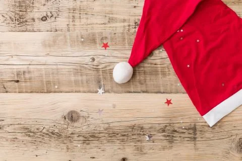 Top view on Santa's hat on retro wooden background with shiny stars. Christma Stock Photos