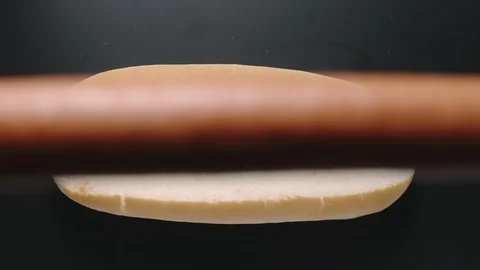 TOP VIEW: Sausage falling into a white bread. Hot dog cooking. Slow motion. Video stock 126567613