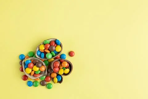 Top view of scattered multi-colored candies in broken Chocolate Easter eggs on Stock Photos