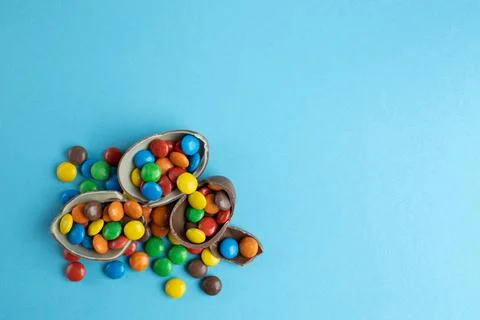 Top view of scattered multi-colored candies in broken Chocolate Easter eggs on Stock Photos