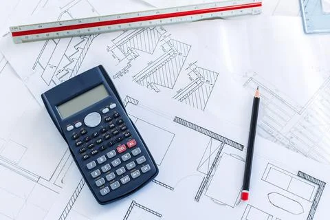 A top view of a scientific calculator on construction blueprints and tools fo Fotos de archivo