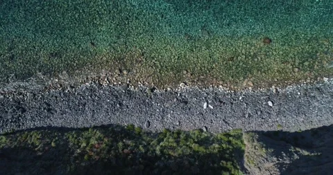 Top view of sea, waves break on high cliff of a rocky mountain and a yacht is 動画素材 154928977
