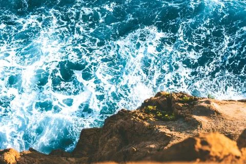 Top view of sea waves hitting rocks on the beach with turquoise blue sea wate Stock Photos