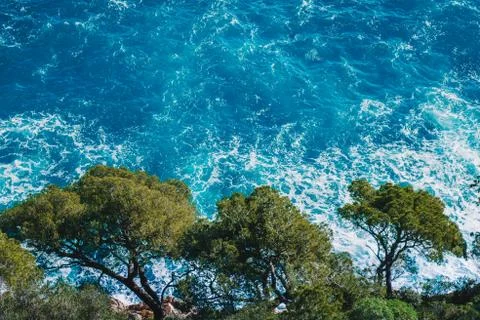 Top view of sea waves hitting rocks on the beach with turquoise blue sea wate Stock Photos