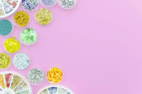 Top view sequins for nails in a jars. Sparkles in a jar. Pink background with Stock Photos
