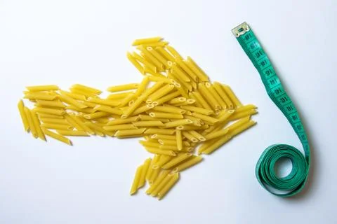 Top view in the shape of an arrow from raw pasta indicates a measuring tape o Stock Photos