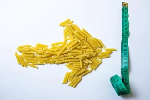 Top view in the shape of an arrow from raw pasta indicates a measuring tape o Foto stock