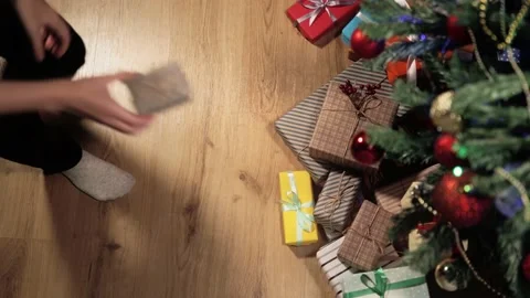 Top view. She puts small gift wrapped in striped green-brown paper tied with Video stock 163451481