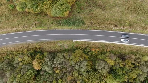 Top view. shooting from a drone. two cars are driving on the road between the Stock Footage 126709866