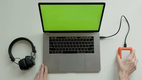 Top View Shot Of Green Screen Laptop, Smartphone And headphones, hdd disc On A Stock Footage 237625577