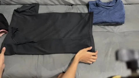 Top view shot of hands folding washed t-shirts Stock Footage 347012086