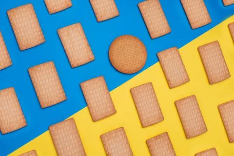 A top view shot of rectangular cookies and one circular on a blue and yellow  Foto stock