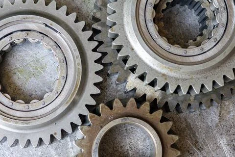 A top view shows interlocking steel gears placed on an industrial metal sur.. Stock Photos