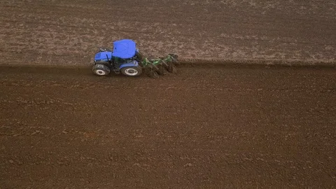 Top view side view of a blue tractor plowing a field, ground furrow Stock Footage 127629024