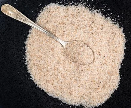 Top view of silver teaspoon in Psyllium husk on black Stock Photos