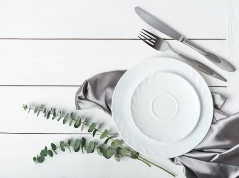 Top view of simple white table setting with silk napkin and green leaves. w.. Stock Photos