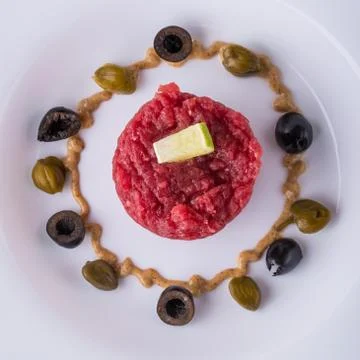 Top view on single portion of tartar steak on white plate Stock Photos