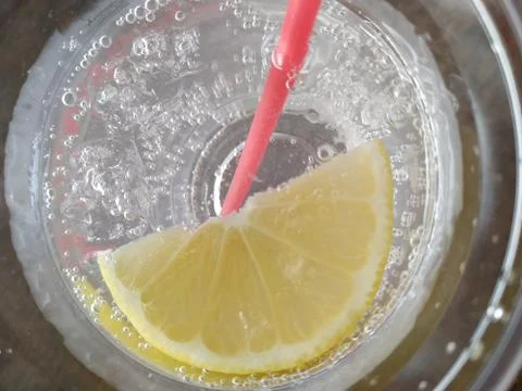 Top view at slice of lemon in a glass with fizzy soda drink with red straw Stock Photos