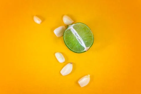 Top view of a slice of lemon surrounded by garlic cloves over a background of Stock Photos