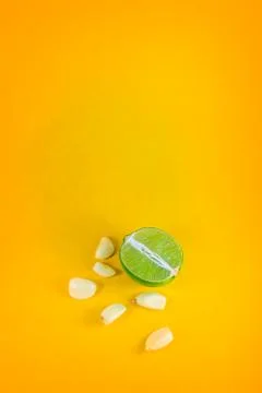 Top view of a slice of lemon surrounded by garlic cloves over a background of Stock Photos