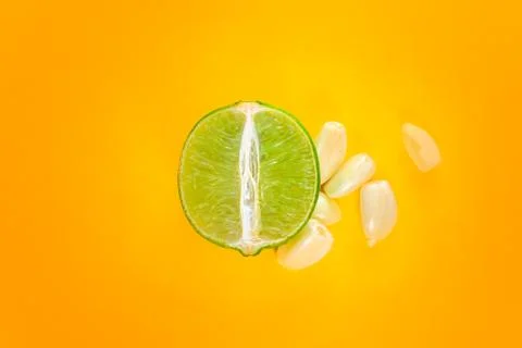 Top view of a slice of lemon surrounded by garlic cloves over a background of Stock Photos