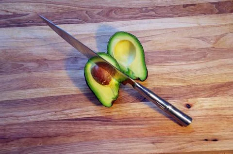 Top View of Sliced Avocado with Sharp Chef Knife on Wooden Cutting Board Stock Photos