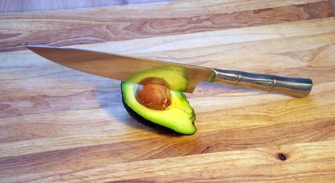 Top View of Sliced Avocado with Sharp Chef Knife on Wooden Cutting Board Stock Photos