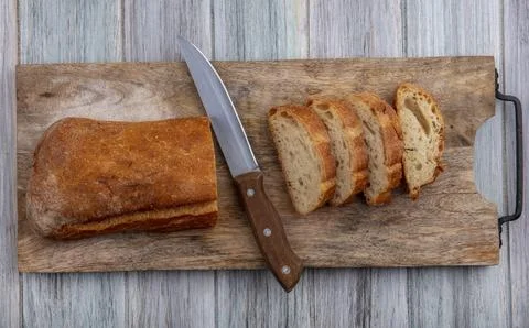 Top view of sliced crusty bread and knife on cutting board on wooden backgrou Foto stock